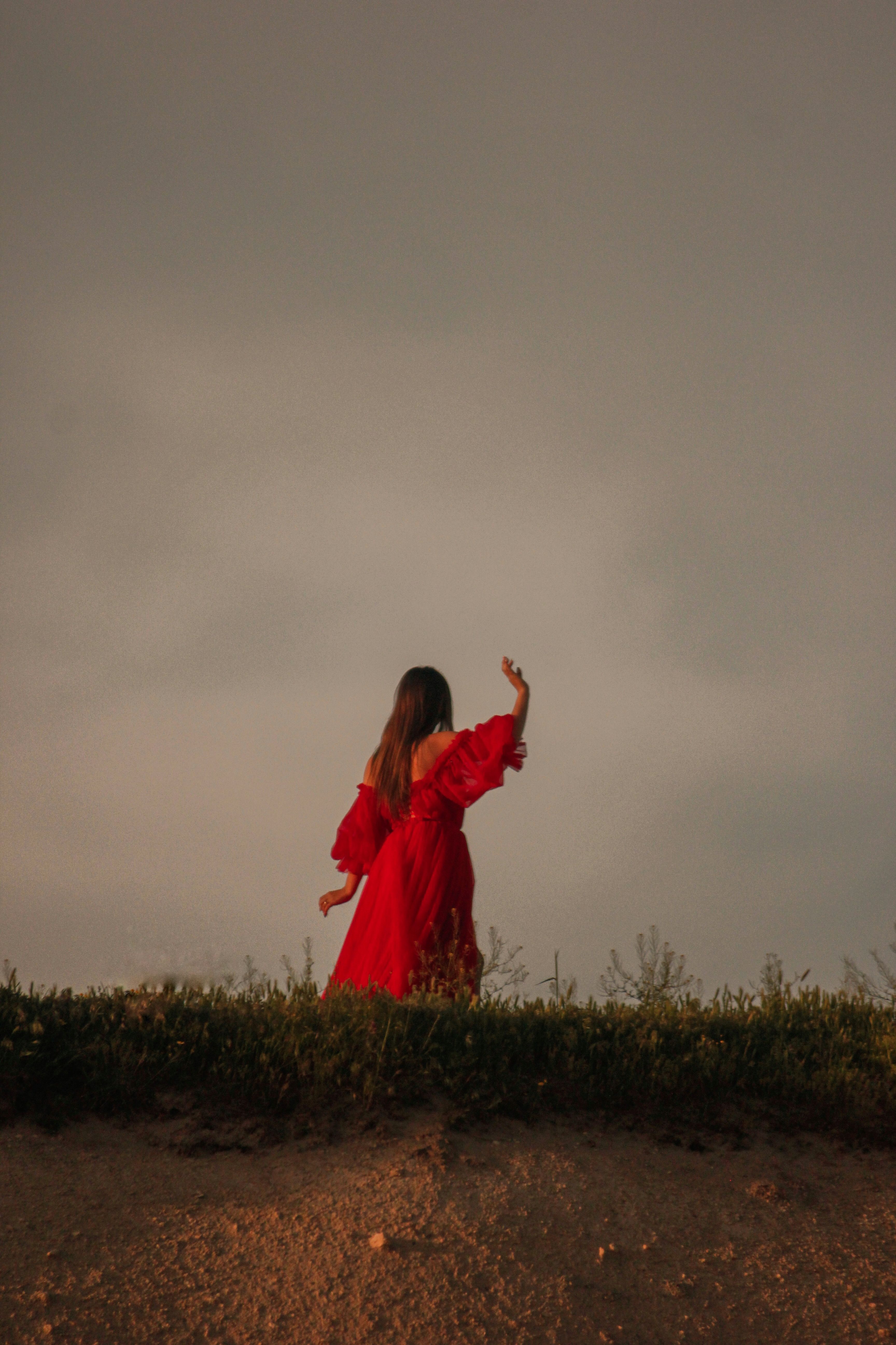 A Woman in Red Dress Walking on Sand · Free Stock Photo