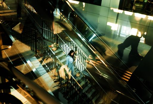 Woman navigating through an abstract, reflective escalator in a modern building.