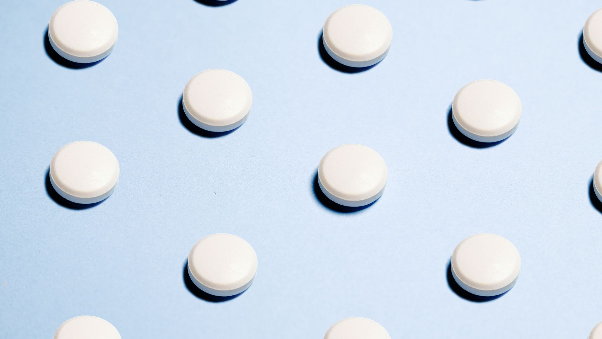 Provigil vs Generic Modafinil: What's the Difference? Array of white pills on a light blue background, ideal for healthcare themes.
