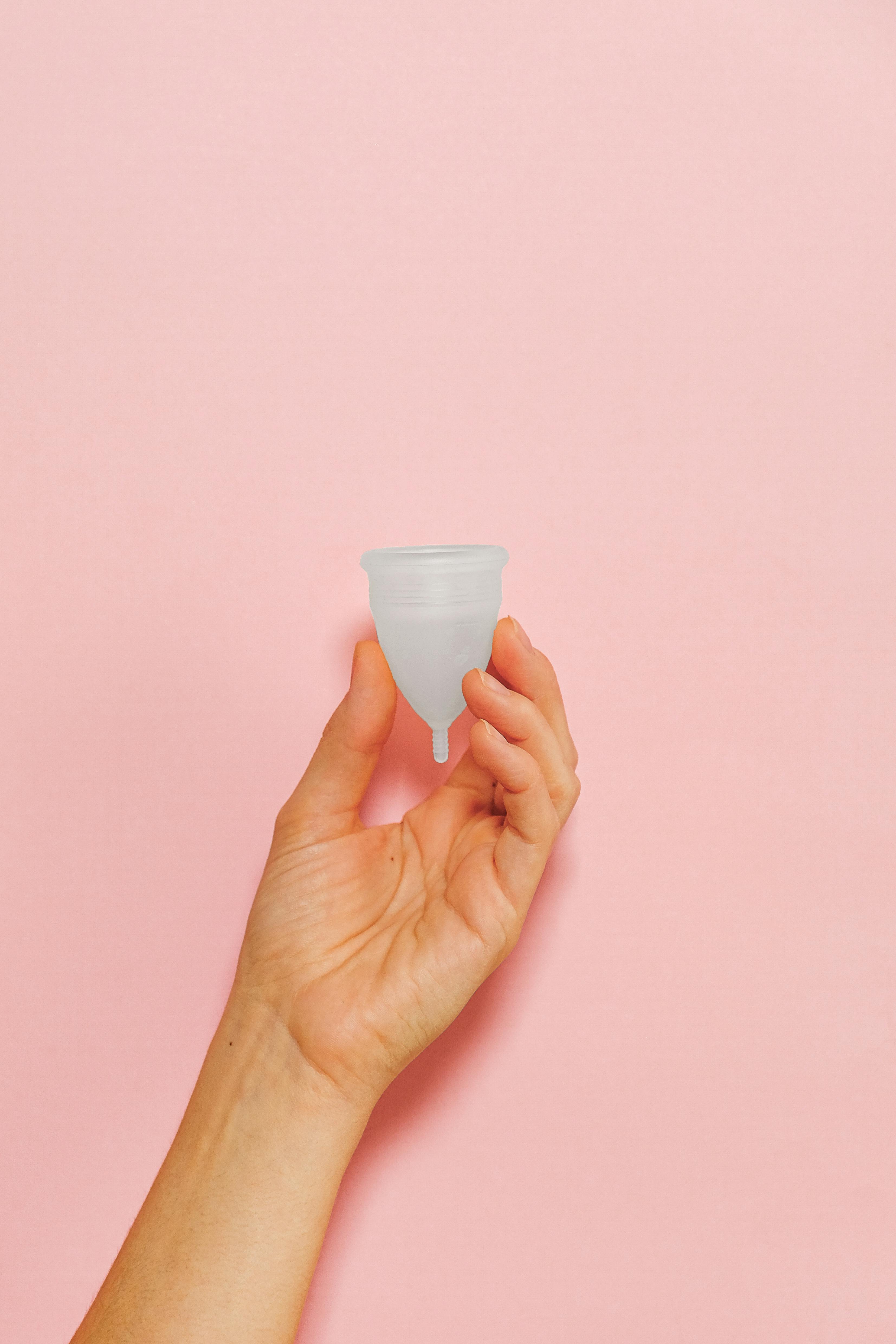 holding white plastic cup on pink background