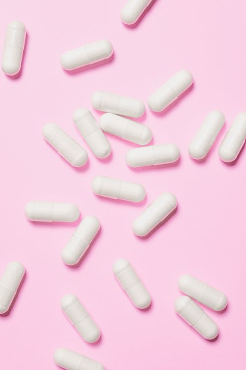 Free White Capsules on Pink Surface Stock Photo