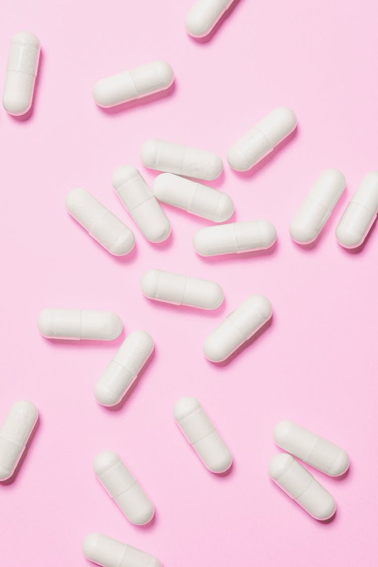 White Capsules On Pink Surface