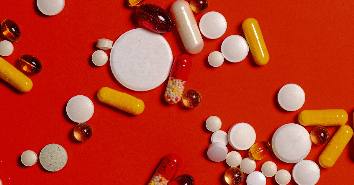 Photo by Anna Shvets A diverse array of pills and capsules scattered on a vibrant red surface.