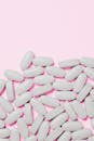 白色药丸散布在软粉色背景上，象征着医疗保健和药物