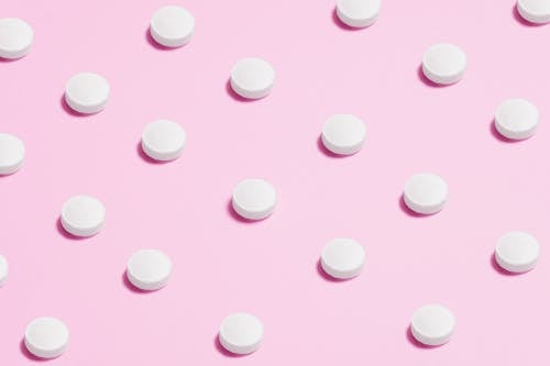 Free White Round Capsule on Pink Background Close-up Photography Stock Photo