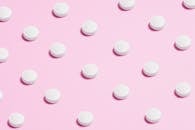 白色药丸铺在淡粉色表面上，体现了医学主题