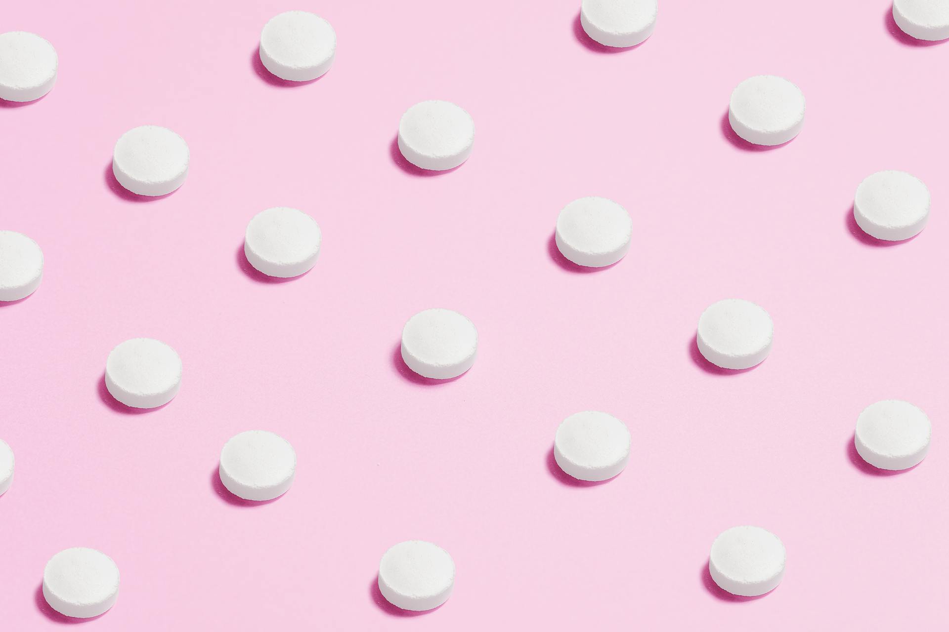 White Round Capsule on Pink Background Close-up Photography