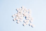 浅蓝色表面上散布着一系列白色药片，非常适合健康相关的内容