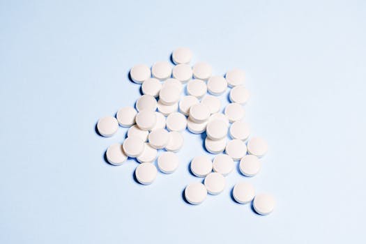 A collection of white tablets scattered on a light blue surface, perfect for health-related content.