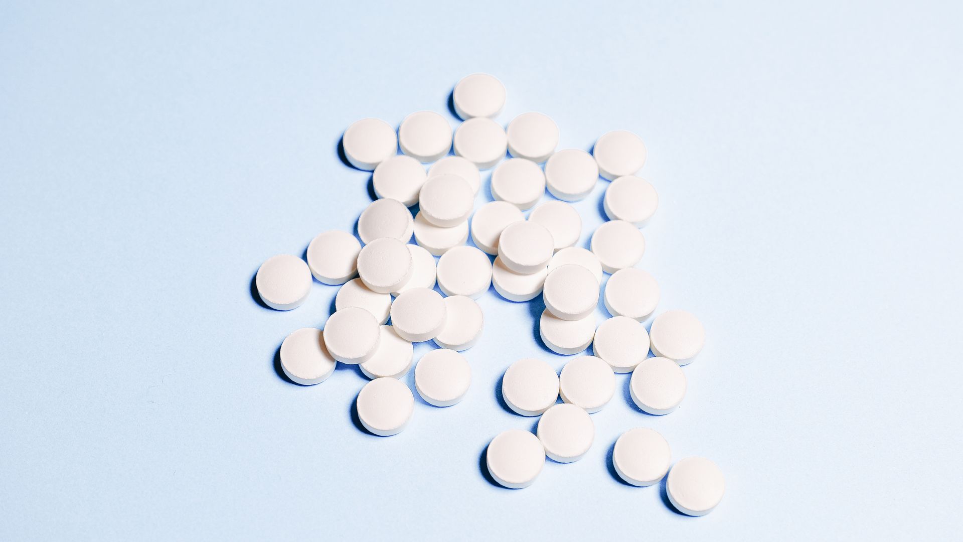 modafinil for ADHD: Guide A collection of white tablets scattered on a light blue surface, perfect for health-related content — modafinil for ADHD