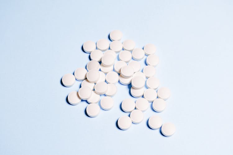 White Round Medication Pills On Sky Blue Surface