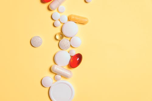 Red and White Medication Pills on Yellow Surface