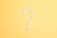 在鲜艳的黄色背景上，白色药丸排列成问号形状