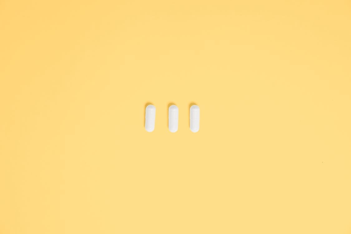 Photo Of Three White Capsule In Yellow Background · Free Stock Photo