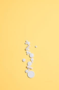 一张极简主义图像上，白色药丸散布在充满活力的黄色背景上，非常适合医疗保健主题