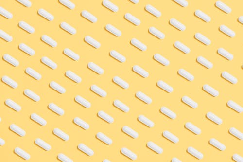 Free White Capsules on Yellow Background Stock Photo