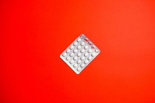 Free Silver Blister Pack on Red Surface Stock Photo