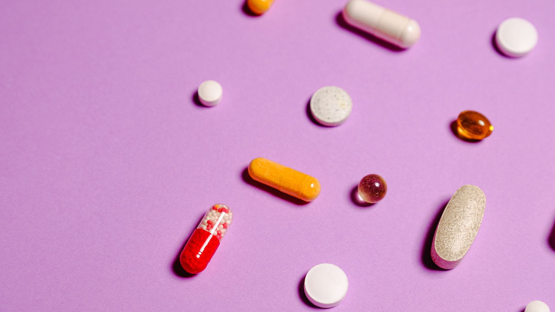 Adrafinil vs Modafinil: Unlocking the Differences A vibrant flat lay of various pills and capsules on a purple surface — adrafinil vs modafinil