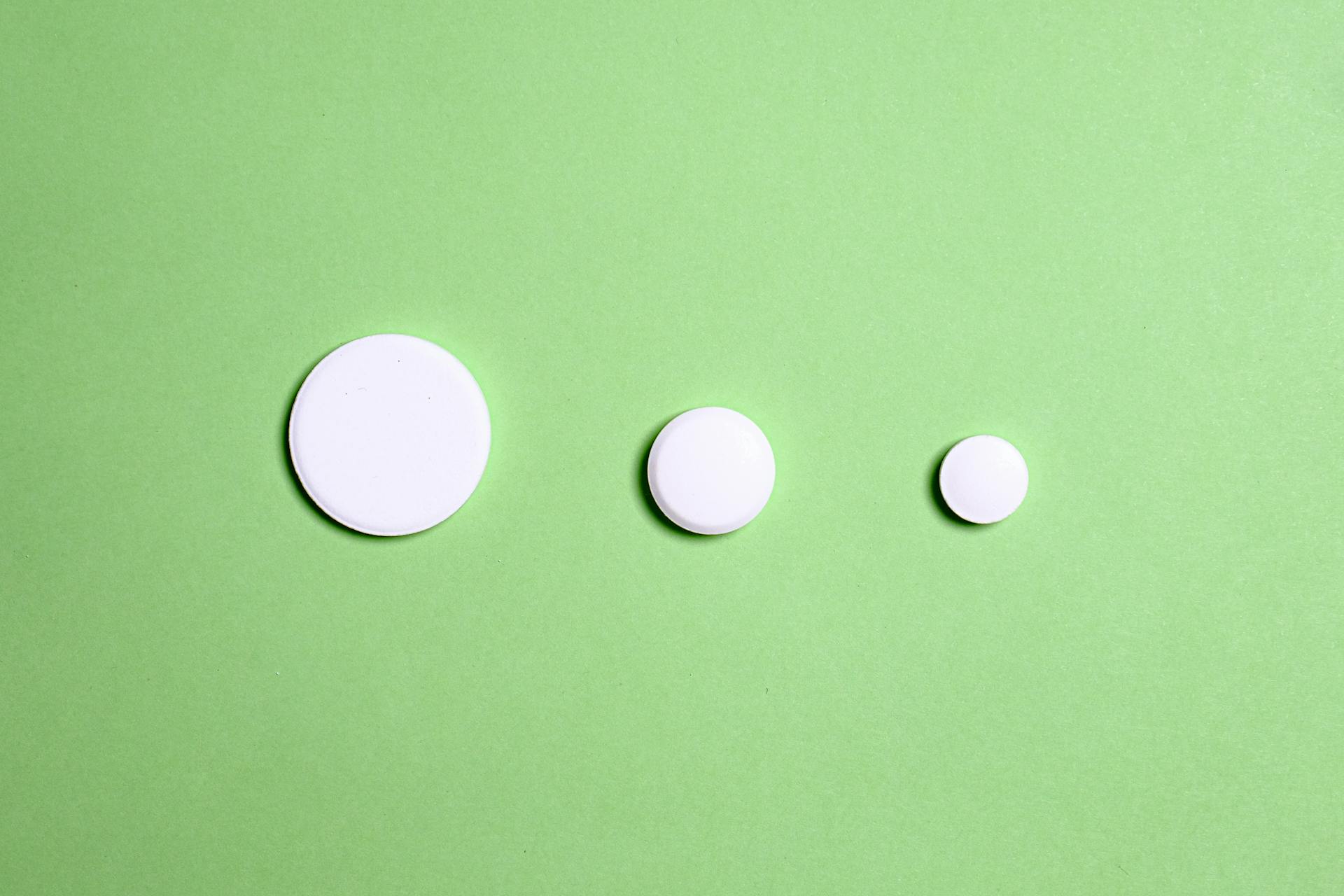 White Round Medication Pill on Green Surface