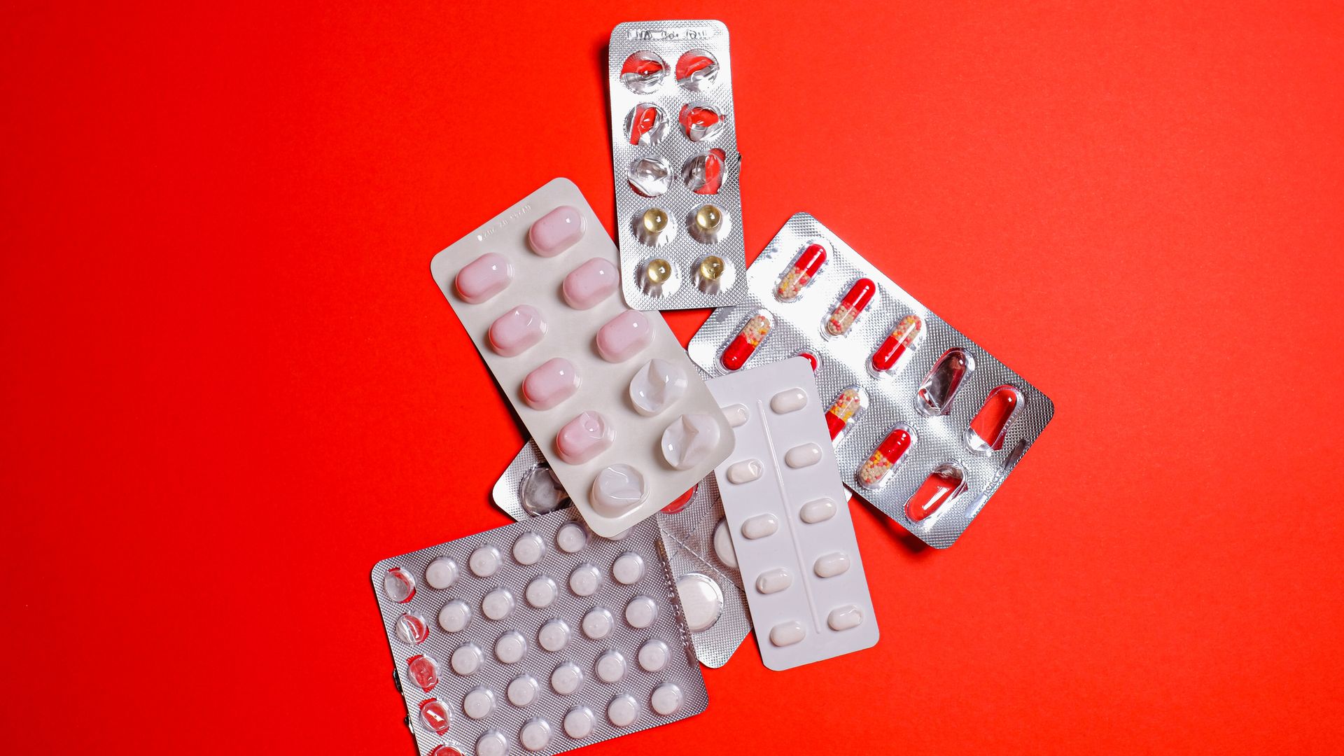 modafinil overdose symptoms: Guide Blister packs with assorted pills over a vibrant red surface. Ideal for healthcare themes — modafinil overdose symptoms