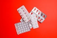 鲜艳的红色表面上展示着泡罩包装中的各种药丸和胶囊