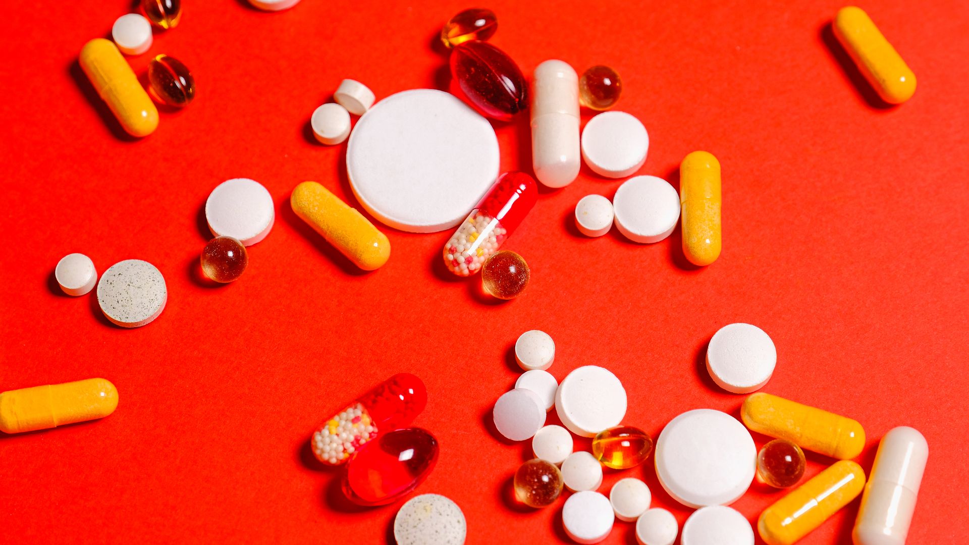 Does Modafinil Show Up on a Drug Test? Variety of pills and capsules scattered on vibrant red backdrop, showcasing diverse medicine forms — does modafinil show up on a drug test