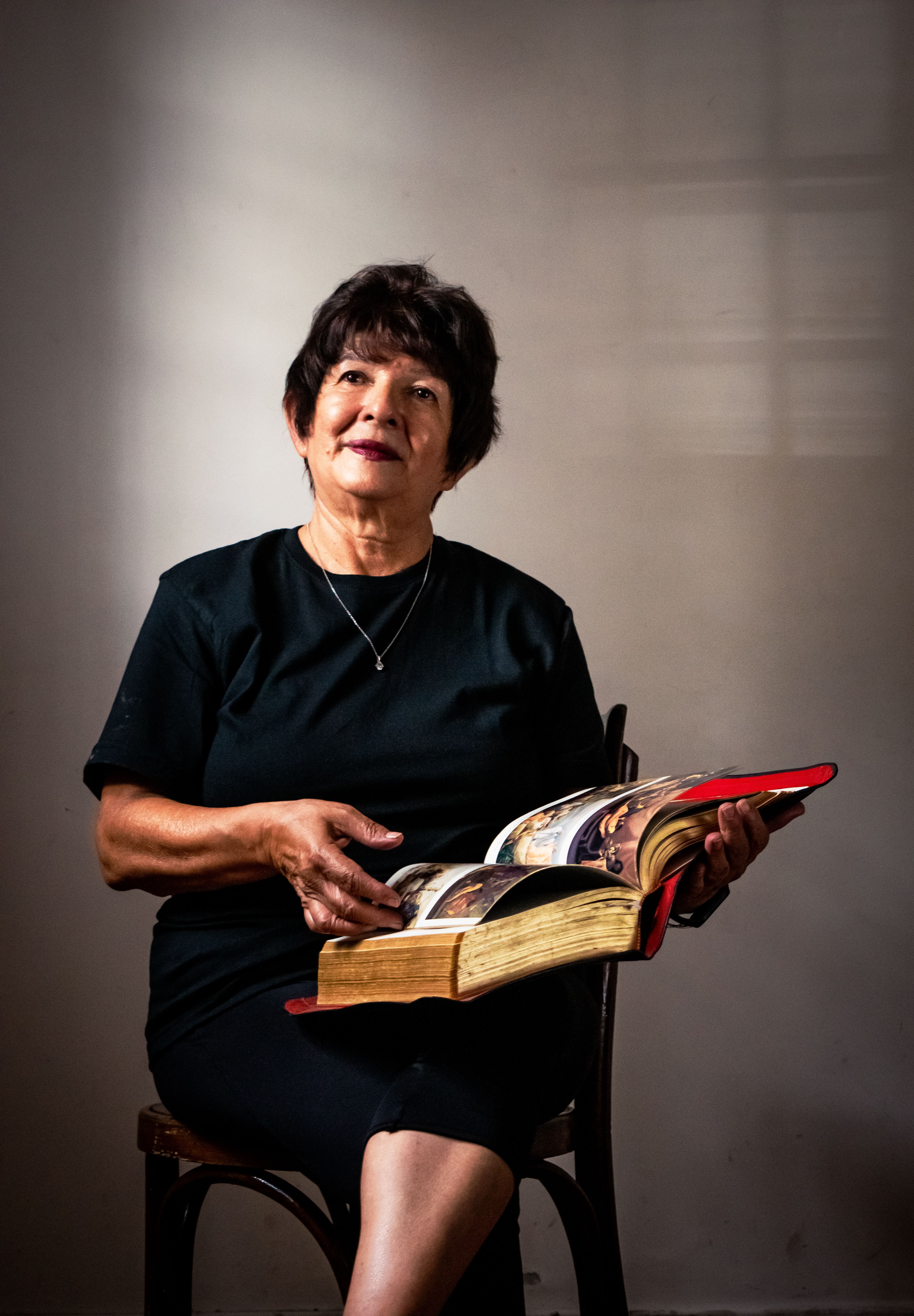 Senior Woman Reading a Large Book Indoors · Free Stock Photo