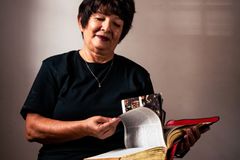 Senior woman reading a large book indoors with focused expression, depicting relaxation and learning.