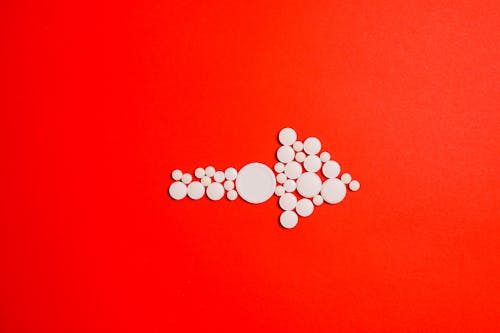 White Round Medication Pill on Red Surface