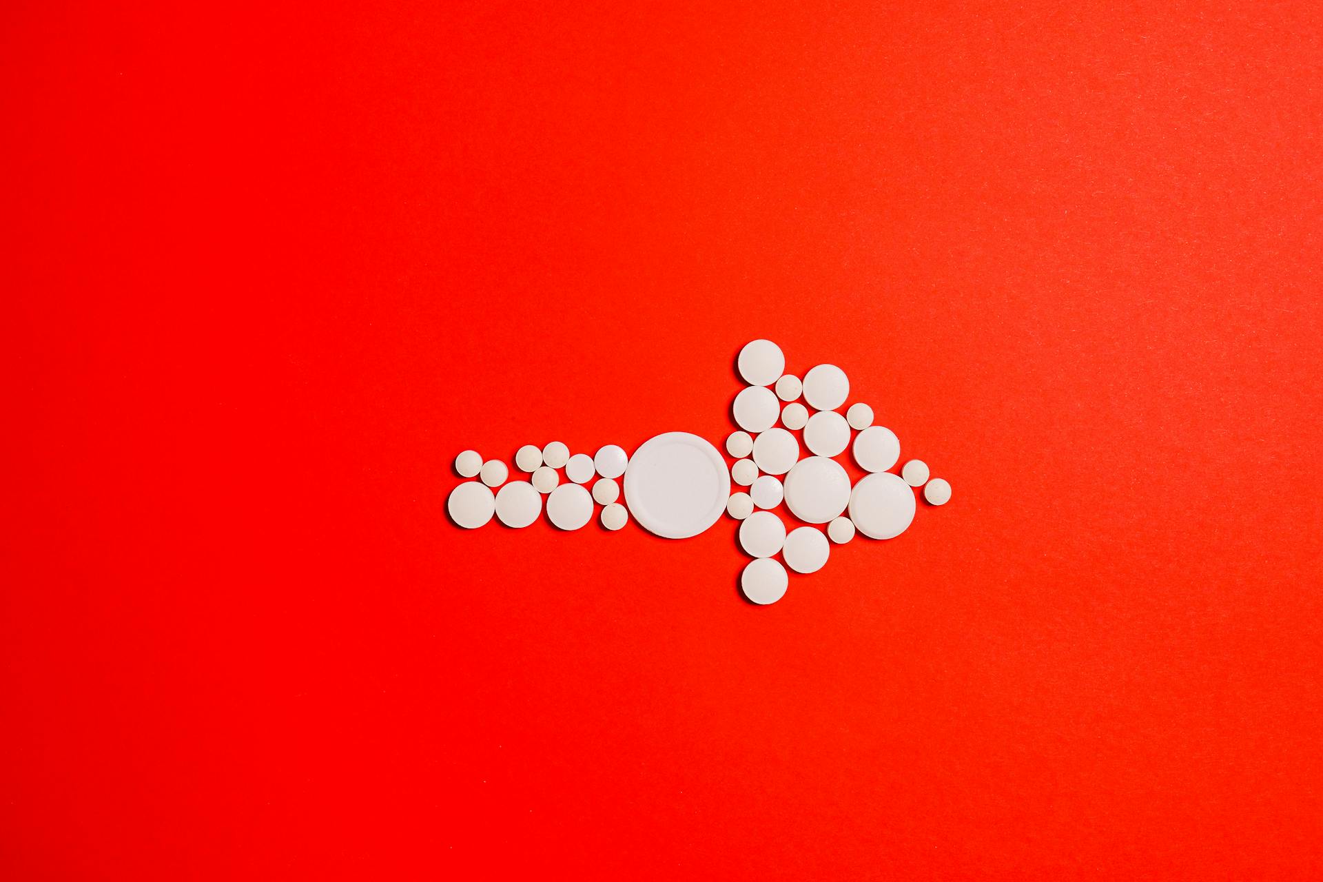 White Round Medication Pill on Red Surface