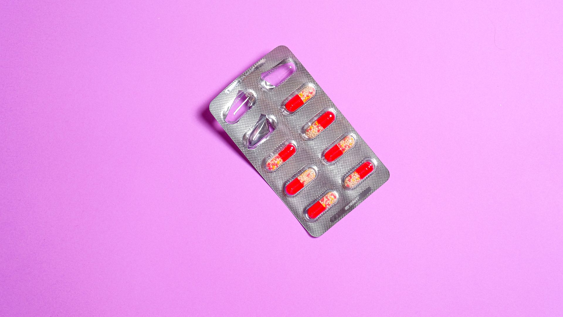 Close-up of a blister pack containing red capsules on a vibrant purple background — modvigil 200mg review