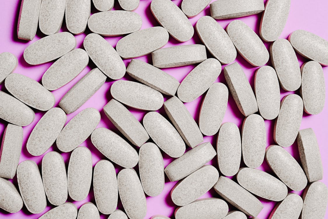 Free White Medication Pills Isolated on Purple background Stock Photo