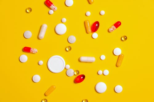 Free Medication Pills on Yellow Surface Stock Photo