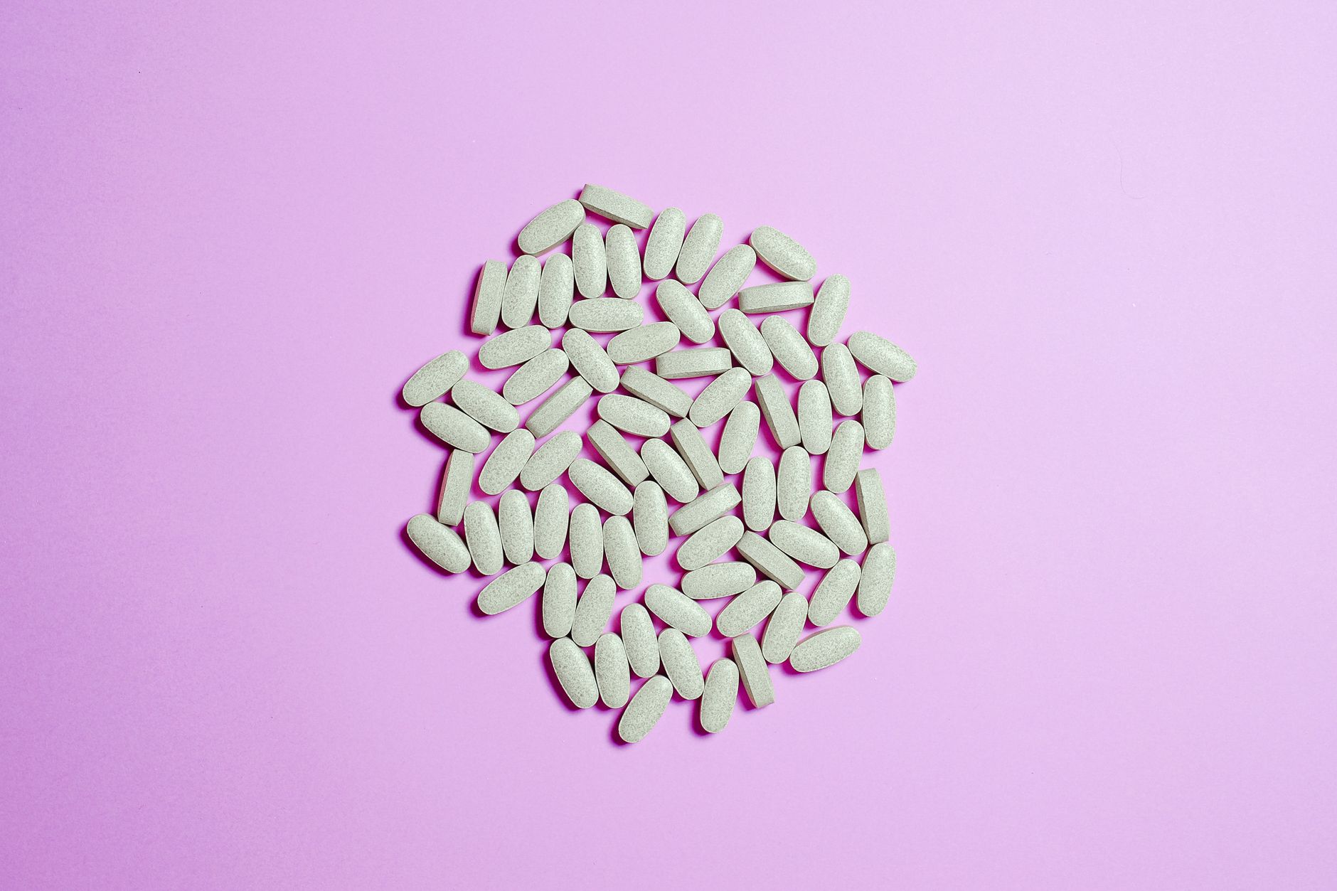 A cluster of white pills on a purple surface, highlighting pharmaceutical themes.