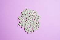 紫色表面上的白色药丸簇突出了制药主题