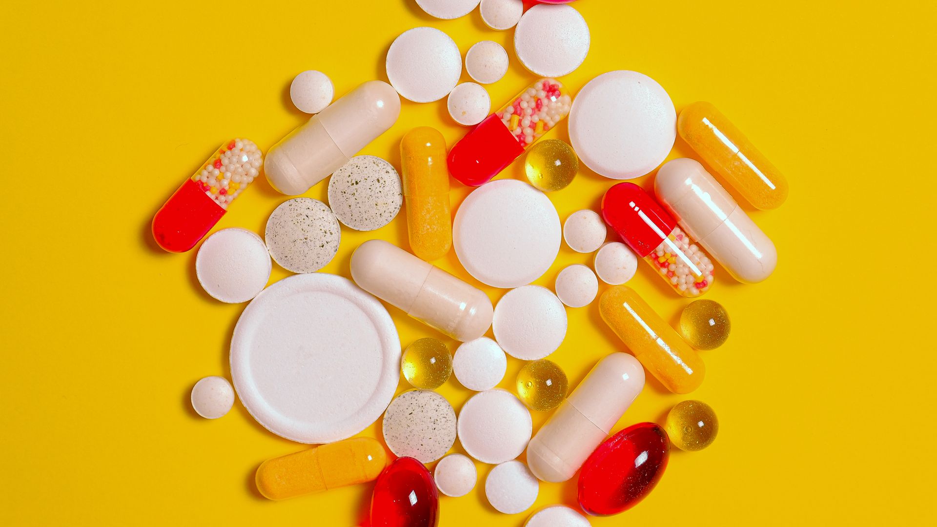 A vibrant assortment of pills and capsules on a bright yellow background, ideal for healthcare themes — provigil generic modafinil