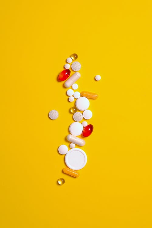 藥物治療藥片和膠囊在黃色背景上孤立