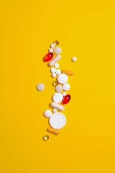 Assorted pills in vibrant colors on a striking yellow background, representing healthcare and medicine.