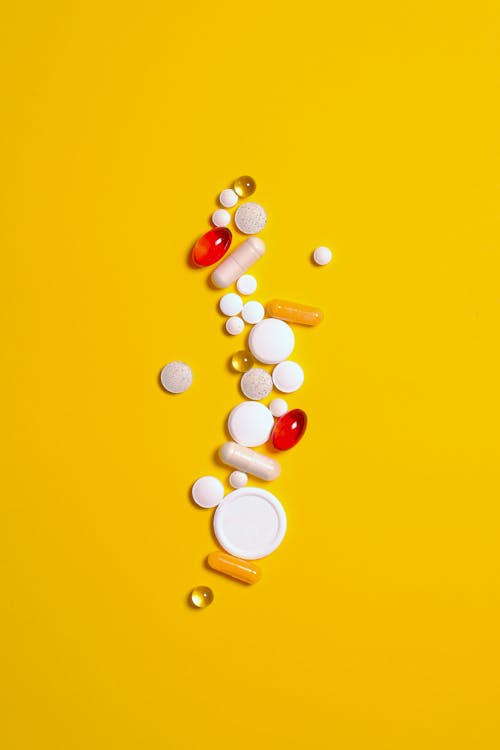 Таблетки и капсулы лекарств, изолированные на желтом фоне