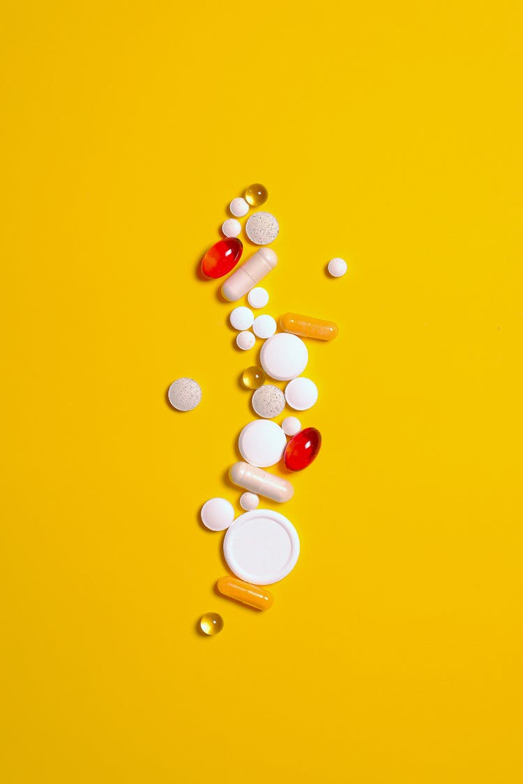 Medication Pills And Capsules Isolated On Yellow Background