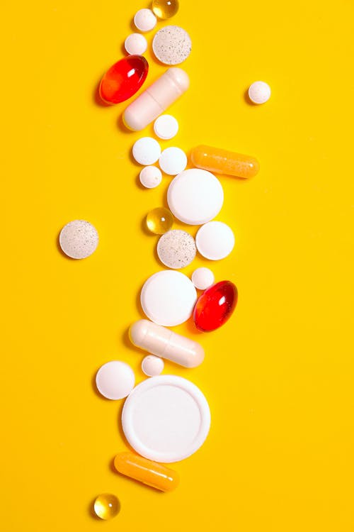 Связка таблеток лекарства на желтом текстиле