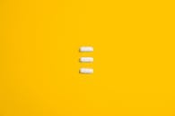 白色药丸排列在鲜艳的黄色背景上，突显了简约与健康
