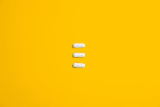 White pills arranged on a vibrant yellow background, emphasizing simplicity and healthcare.
