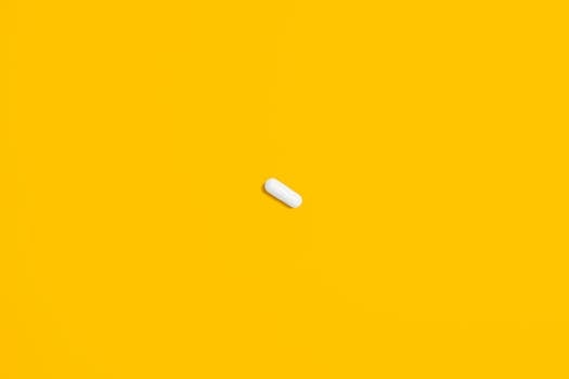 一颗白色药丸置于亮黄色背景之上，凸显了其简洁与重点