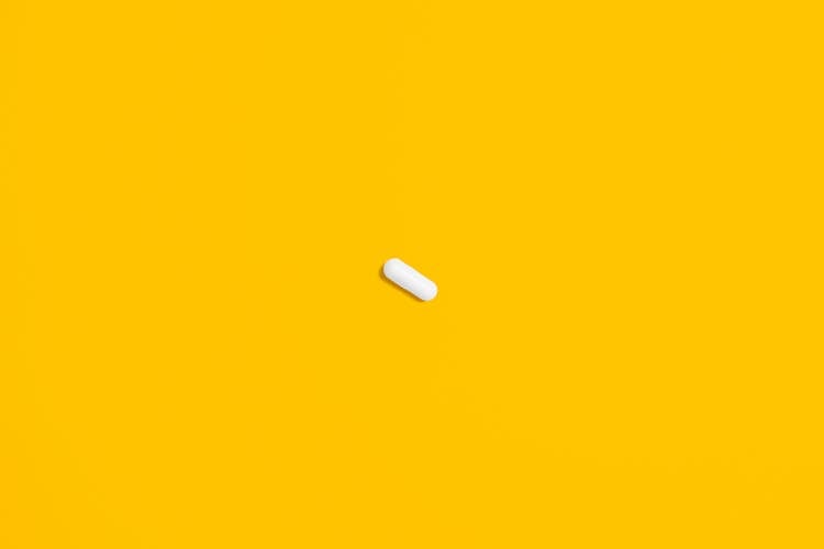 White Pill On Yellow Surface