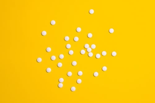 White Medication Pills Isolated on Yellow background