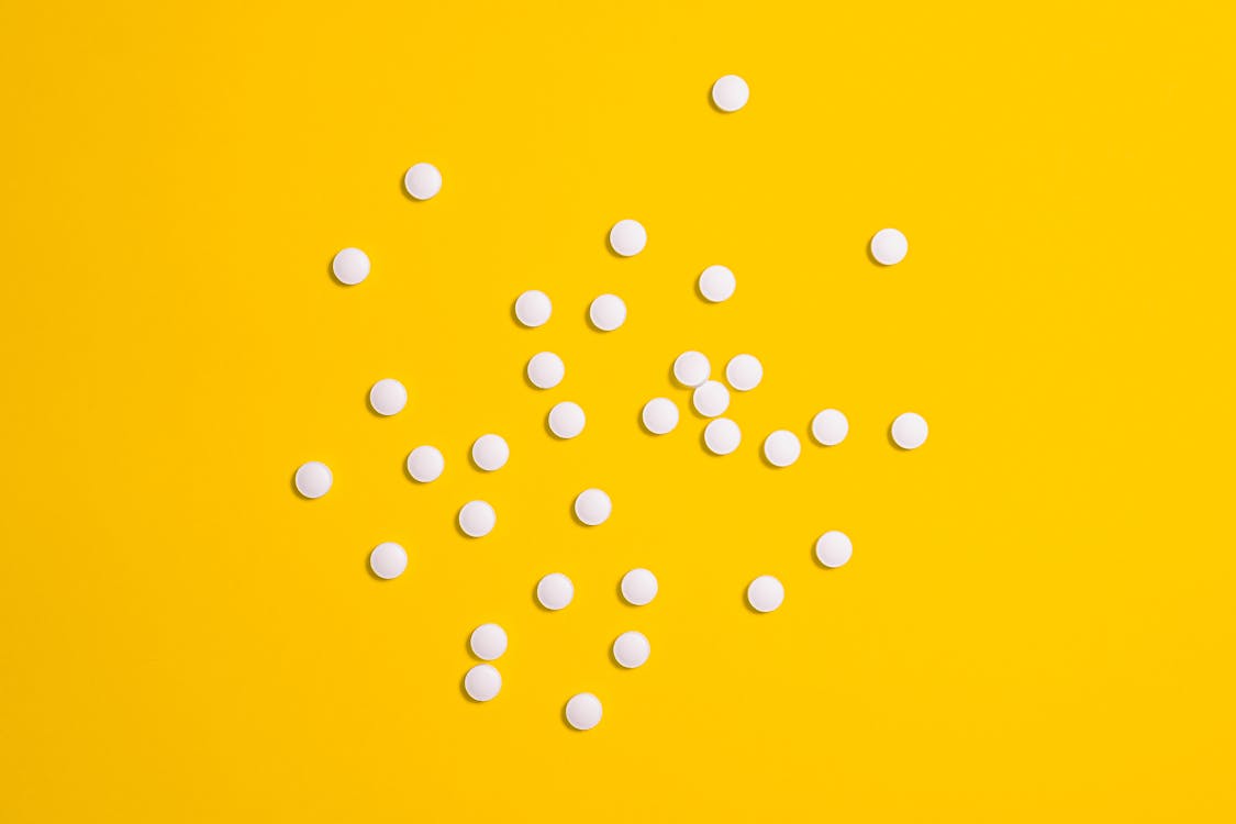 White Medication Pills Isolated on Yellow background