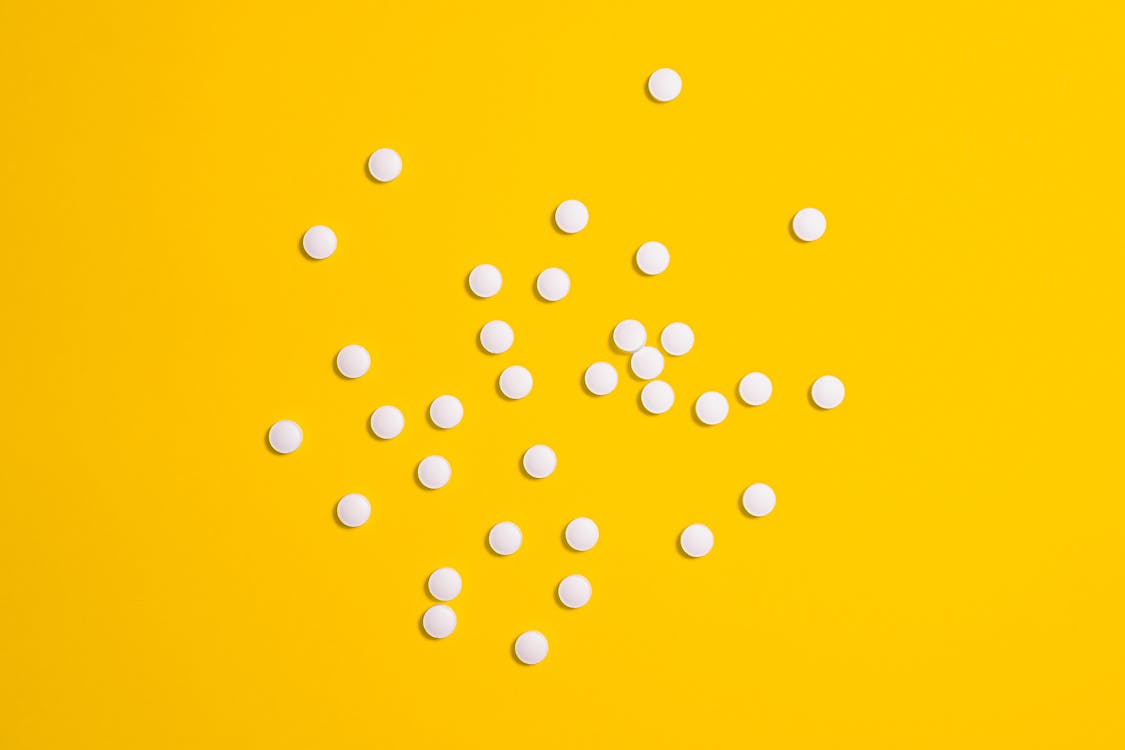Free White Medication Pills Isolated on Yellow background Stock Photo