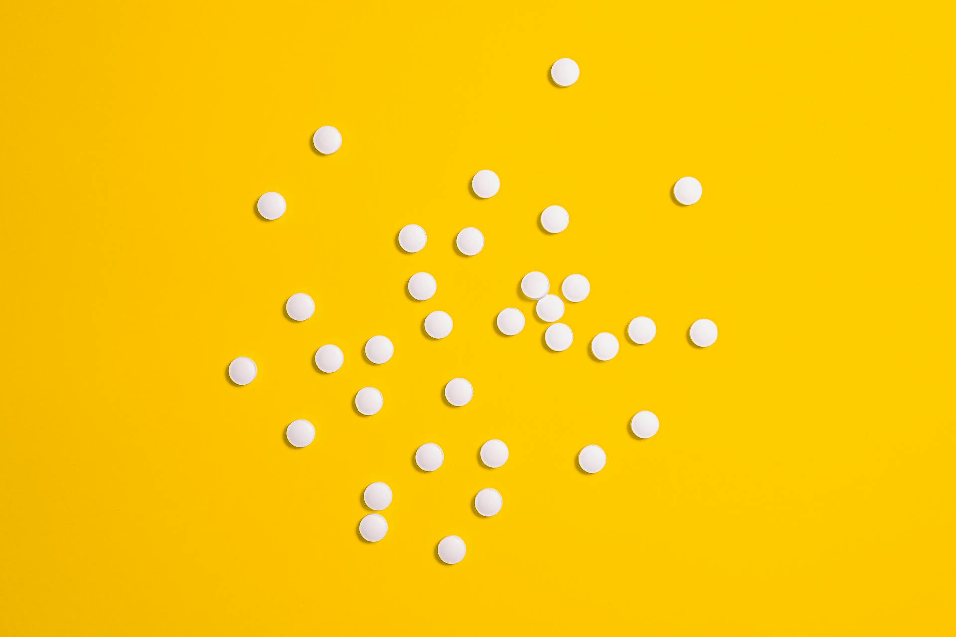 White Medication Pills Isolated on Yellow background