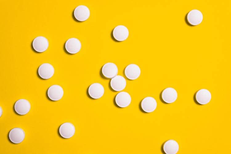 White Medication Pills Isolated On Yellow Background